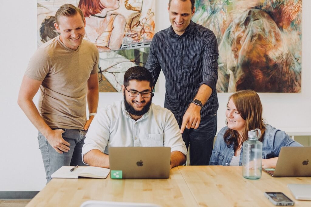 Four founders smiling around a laptop at a table