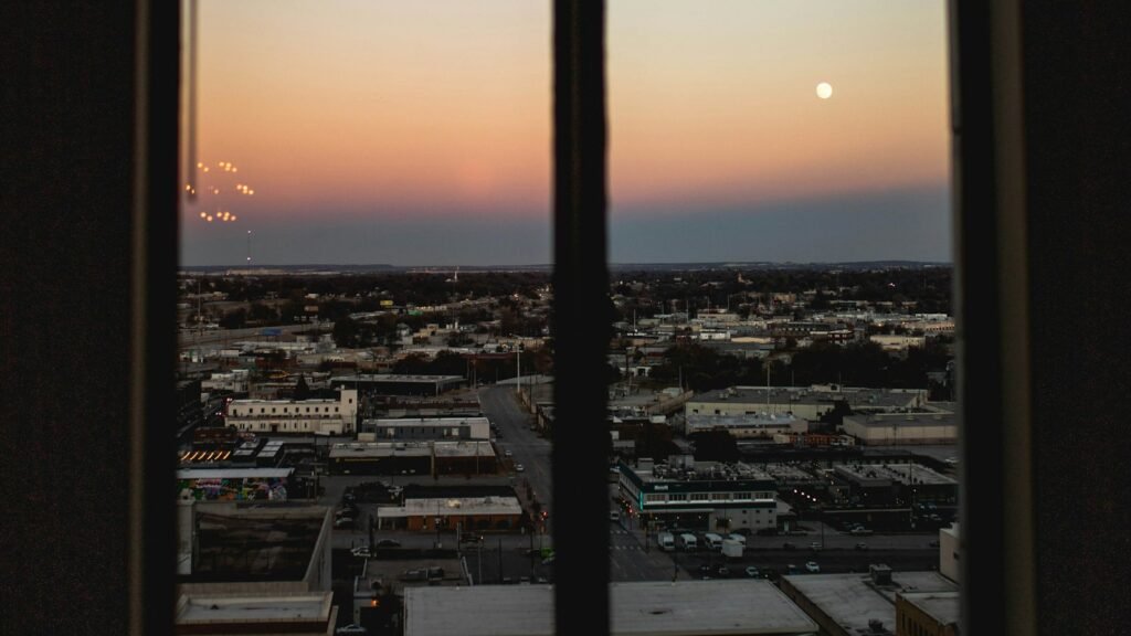 Office window looking out over a city at sunset, the view from a job you hate while you build your way out