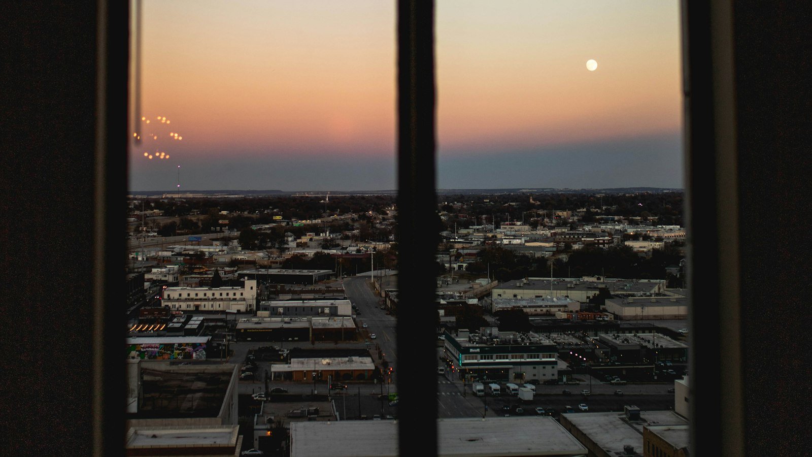 Office window looking out over a city at sunset, the view from a job you hate while you build your way out